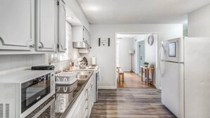 A modern kitchen with white cabinets, a built-in microwave, and a stainless steel sink. - Judy Lynn Collective (Memphis)