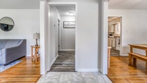 A modern interior with a grey sofa, a wooden bench, and a hallway leading to a kitchen. - Judy Lynn Collective (Memphis)