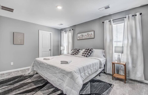 A bedroom with a bed, a nightstand, a lamp, and a window with curtains. - Crievewood Guesthouse (Memphis)