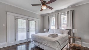 A bedroom with a large bed, a ceiling fan, a nightstand, and a window with curtains. - Parkway Nest (Memphis)