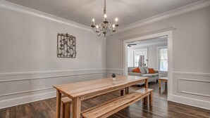A spacious room with a wooden dining table and benches, a chandelier, and a modern art piece on the wall. - Parkway Nest (Memphis)