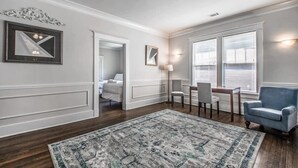 A spacious living room with a large rug, a blue armchair, a dining table with chairs, and a doorway leading to another room. - Parkway Nest (Memphis)