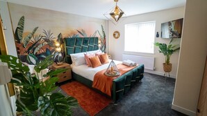 A bedroom with a bed, a nightstand, a wall-mounted shelf, a window, and a plant. - Luxury 5BR Home | Hot Tub | EV-Friendly Stay (West Bromwich)