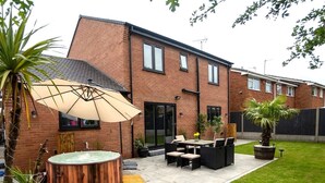 A backyard with a hot tub, outdoor seating, and a large umbrella. - Luxury 5BR Home | Hot Tub | EV-Friendly Stay (West Bromwich)