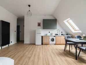 A modern kitchen with a built-in washing machine, a dining area with a table and chairs, and a skylight. - Wilson Park Serene Studio #4 (Poznań)