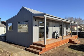 A modern single-story building with a covered porch, large windows, and a wooden deck.