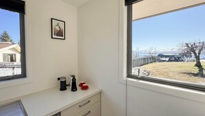 A kitchen with a window, a coffee maker, and a framed picture on the wall. - Roto Cottage - Lake Tekapo (Lake Tekapo)