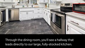 A large, fully-stocked kitchen with white cabinets, a stainless steel dishwasher, and a red microwave. - NWA Getaway Pool, Arcade, Trails (Springdale)