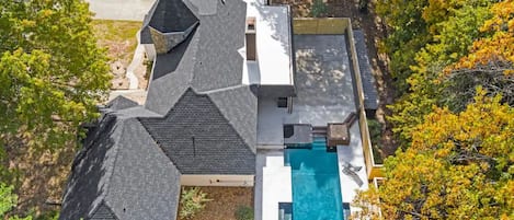 Uma casa com uma piscina grande, cercada por árvores e um gramado bem cuidado.