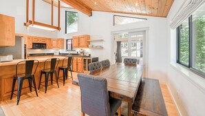 A modern kitchen with wooden cabinets, a large island with bar stools, and a dining table.