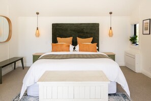 Ein Schlafzimmer mit Bett, Nachttischen, einer Bank, einem Heizkörper und einer Hängeleuchte.