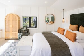 A bedroom with a bed, a wardrobe, a chair, a window, and a mirror.