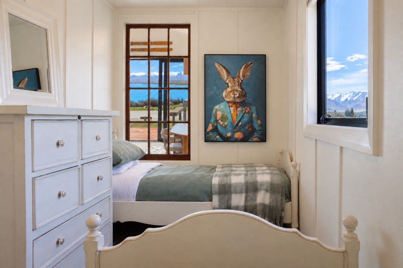 A bedroom with a bed, dresser, and a painting of a rabbit on the wall.