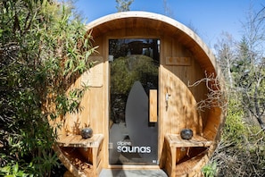Eine hölzerne Sauna mit Tür, zwei seitlichen Bänken und einem Schild mit der Aufschrift 'alpine saunas'.