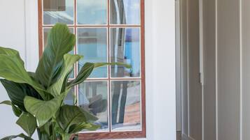 A room with a wooden table, a potted plant, and a window with a view of the outdoors.