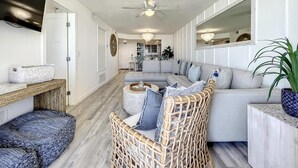 A modern living room with a sectional sofa, a wicker chair, and a round coffee table.