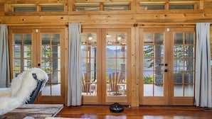 A wooden interior with large glass doors leading to an outdoor patio. - NEW! Views of Whitefish Lake, Wood Burning Fireplace, Cozy Cabin (Whitefish)