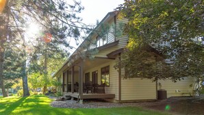A two-story house with a covered porch, a lawn, and trees. - Mountain Harbor Hideaway! Walking distance to Whitefish Lake (Whitefish)