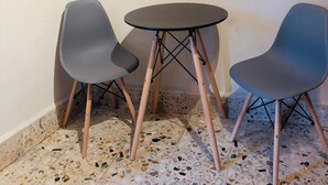 Un coin avec deux chaises grises et une petite table ronde aux pieds en bois.