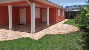 Un edificio con un patio techado, un sendero adoquinado y un césped.