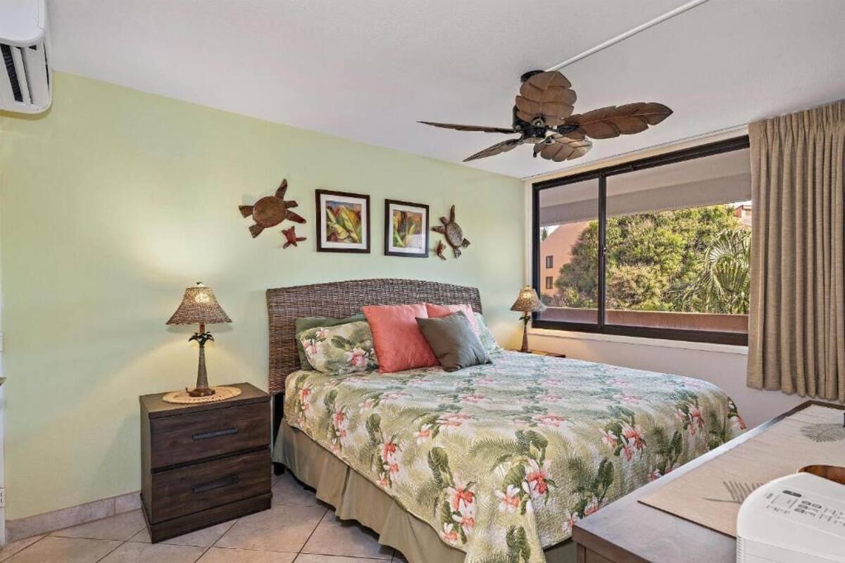 A bedroom with a bed, nightstands, a ceiling fan, and a window with curtains.