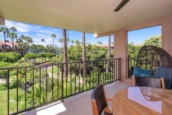 A balcony with a view of a landscaped garden and palm trees. - Kamaole Sands (Kihei)