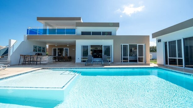 A modern two-story house with a swimming pool, outdoor seating, and large windows. - Ocean View • Style • Freedom (Casa Linda)
