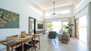 A spacious living area with a dining table, chairs, a sofa, and a TV. - Ocean View • Style • Freedom (Casa Linda)