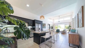 A modern kitchen with a central island, bar stools, and a large plant. - Ocean View • Style • Freedom (Casa Linda)