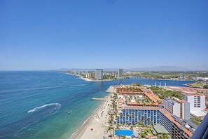 A coastal cityscape with a beach, hotel buildings, and a clear blue sky.