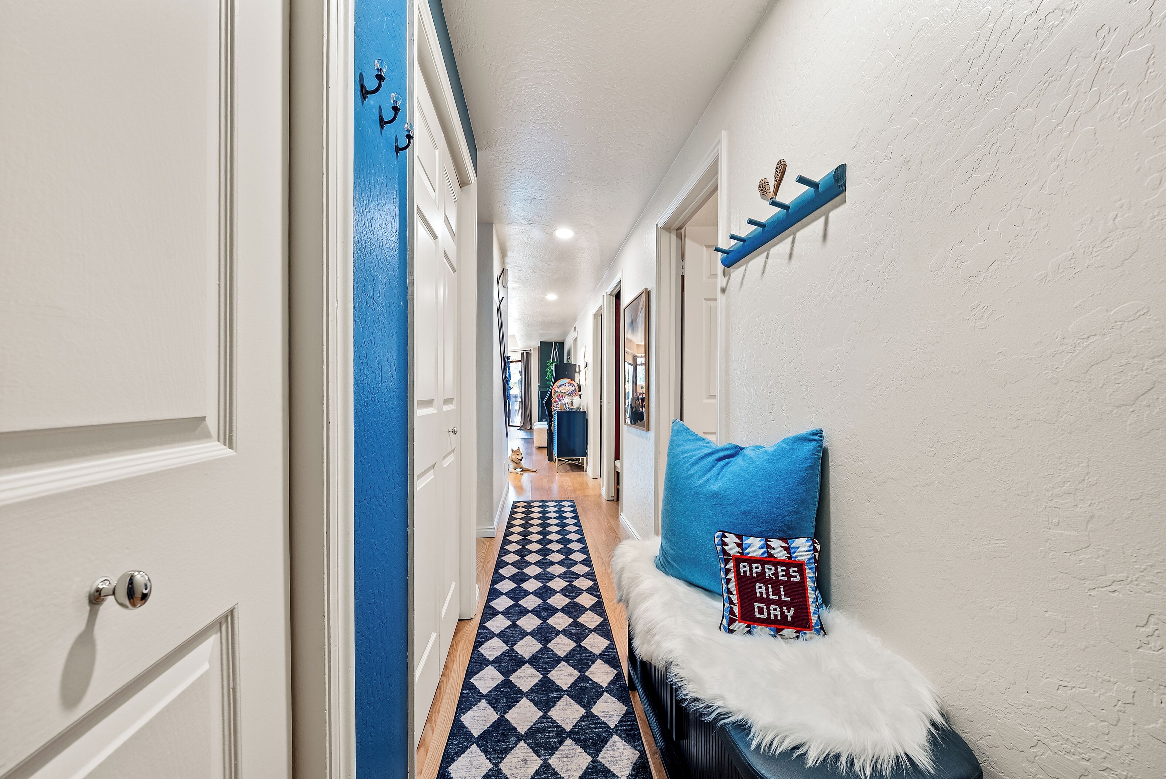 Un pasillo con suelo a cuadros, una puerta blanca y una pared azul.