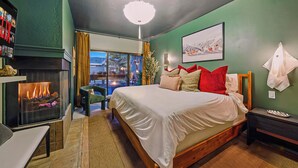 A bedroom with a large bed, a fireplace, a view of the outside, and a green wall. - Après All Day! 3B Walk to Lifts Firepit, Poker, Ski Room, Disco Balls, Views! (Park City)