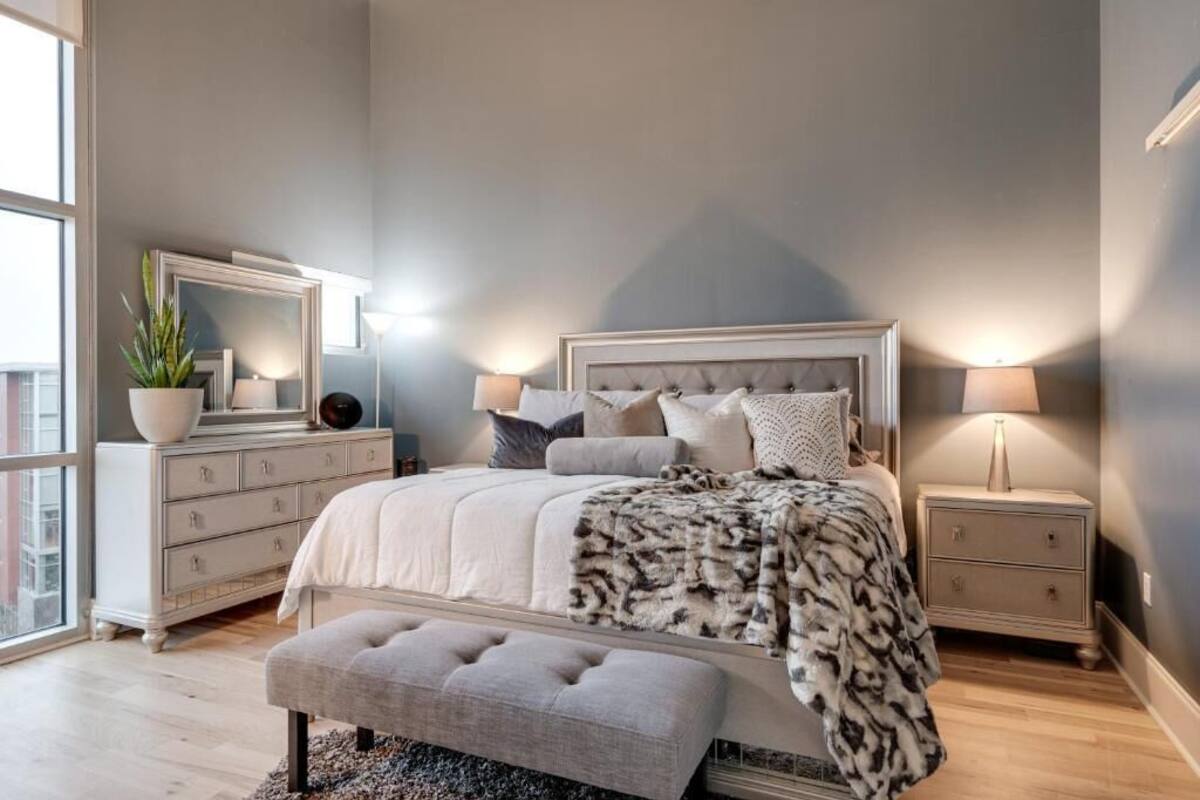 A bedroom with a large bed, a dresser, a nightstand, and a mirror.