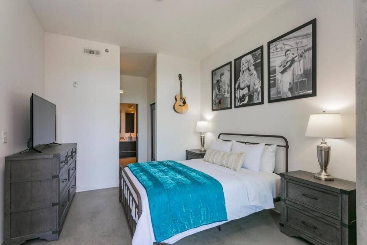 A bedroom with a bed, a dresser, a TV, and framed pictures on the wall.