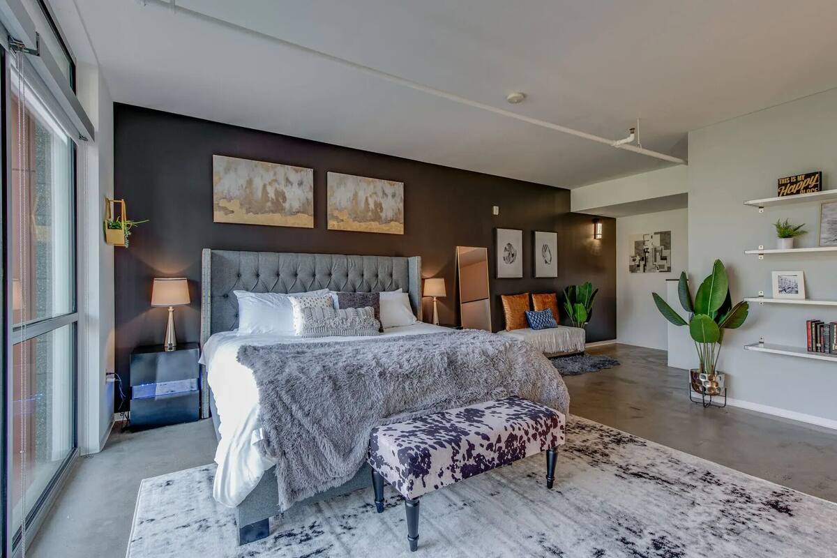 A modern bedroom with a large bed, bedside tables, a bench, and artwork on the walls.
