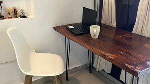 Una habitación pequeña y moderna con un escritorio de madera, una silla blanca y una computadora portátil.