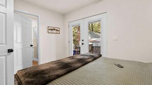 Una habitación con cama, puerta y vistas al exterior.