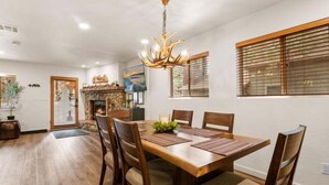 Un comedor con una mesa de madera, seis sillas, una araña y una chimenea.