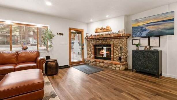 Una sala de estar con chimenea de piedra, sofá de cuero y un cuadro grande en la pared.