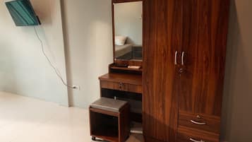 A wooden wardrobe with a mirror, a small stool, and a TV mounted on the wall.