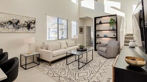 A modern living room with a sofa, coffee table, and armchairs, a bookshelf, and a TV. - Queen Creek Vacation (Chandler)