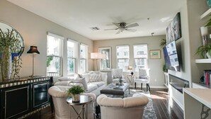 A spacious living room with a large window, a ceiling fan, and a bookshelf. - Queen Creek Vacation (Chandler)