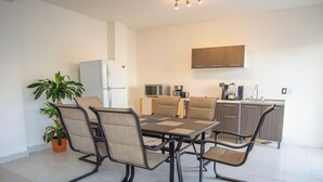 A modern kitchen with a dining area, including a table with chairs, a refrigerator, a microwave, and a sink. - Modern 2-Bedroom Condo with A/C in Stunning Los Cabos (MUNICIPIO LOS CABOS)