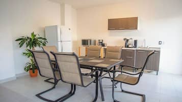 A modern kitchen with a dining area, including a table with chairs, a refrigerator, a microwave, and a sink.