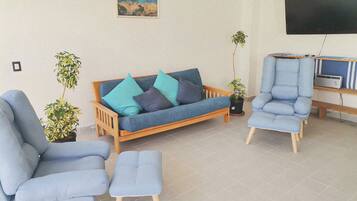 A living room with a sofa, two armchairs, a coffee table, and two potted plants.