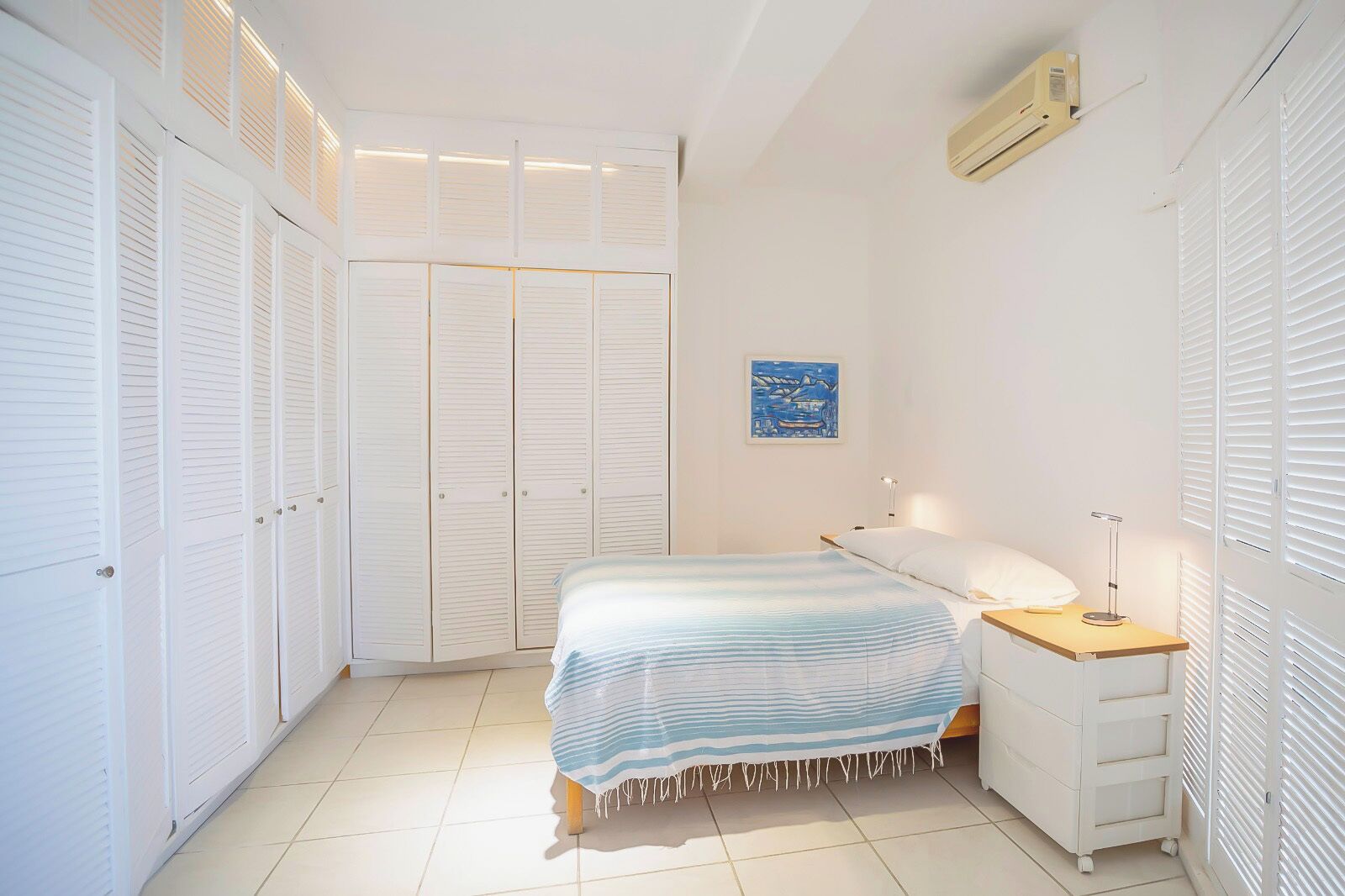 A bedroom with a bed, bedside table, lamp, and a wardrobe with multiple doors.