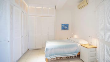 A bedroom with a bed, bedside table, lamp, and a wardrobe with multiple doors.