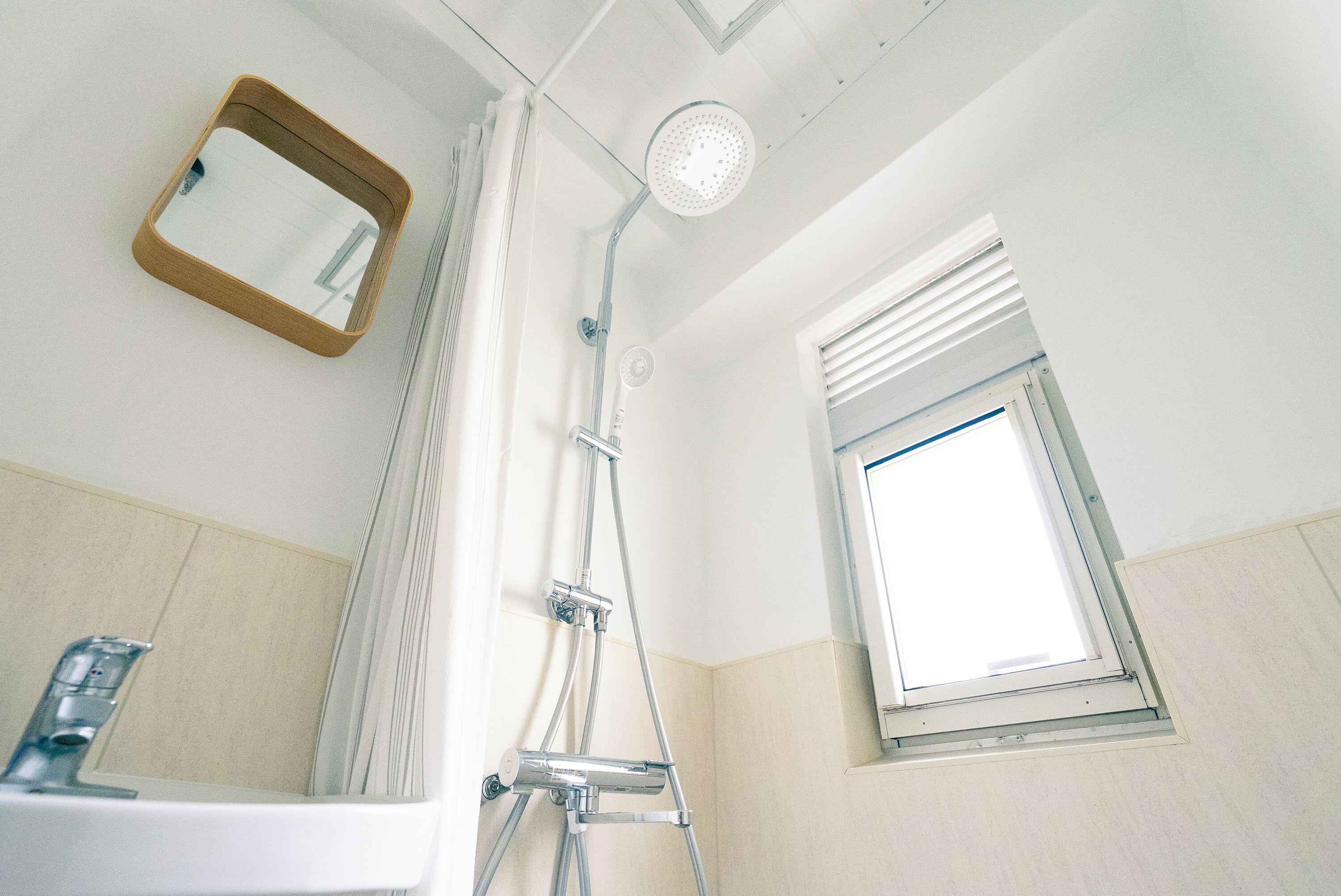 A bathroom with a shower, a window, and a mirror.