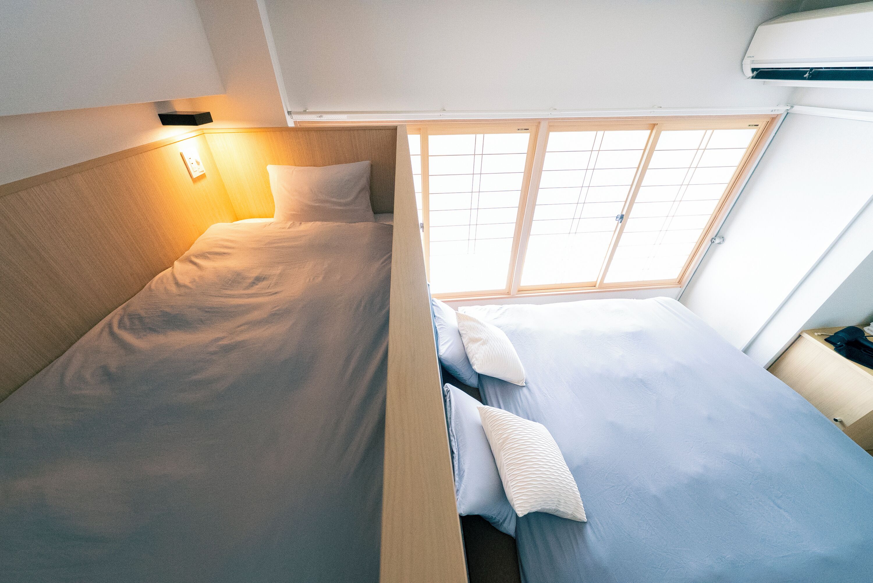 A compact bedroom with two beds, a skylight, and a bedside table.