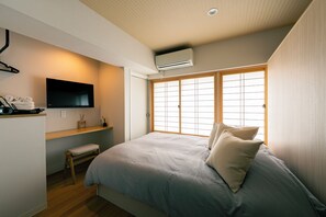 Un dormitorio con cama, televisor, banco y ventana con vistas.